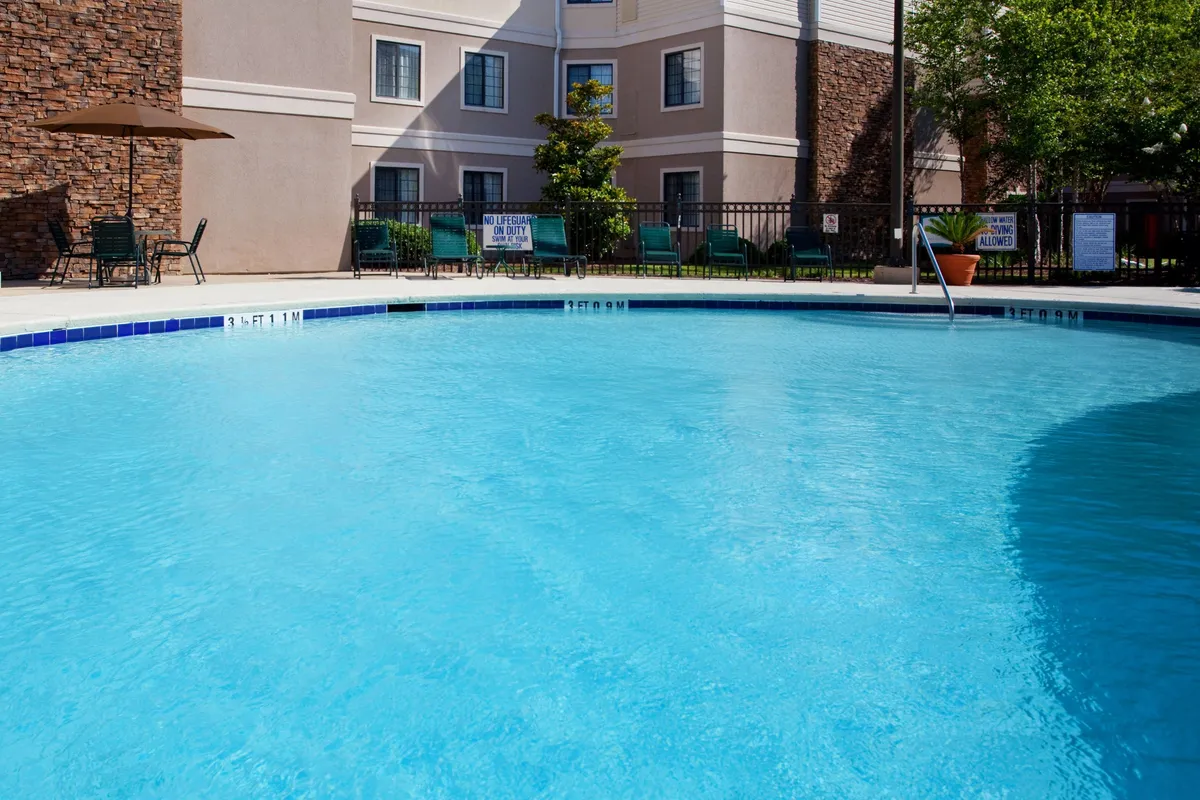 This exterior shot showcases a sparkling swimming pool surrounded by lounge chairs and umbrellas, with the hotel's facade in the background. The mood is relaxing, suggesting guests enjoying a sunset swim, lounging poolside with a book, or socializing after a busy day.